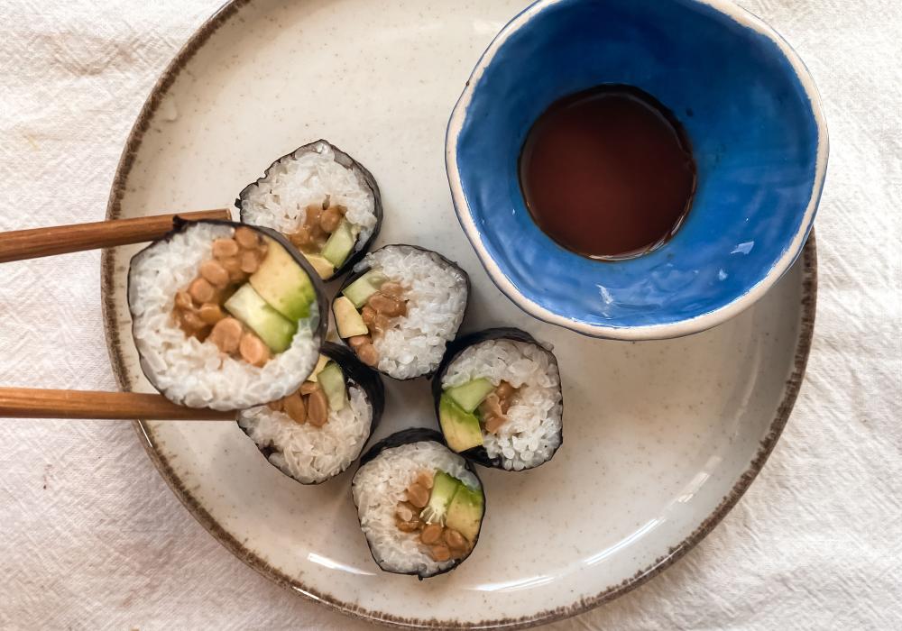 white plate with natto sushi and a blue bowl with soy sauce
