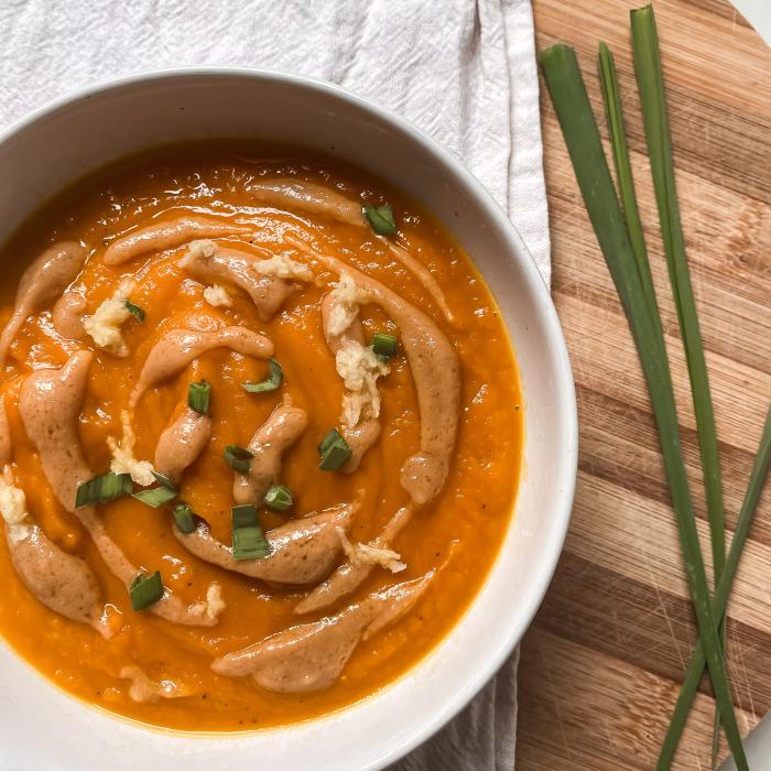 Sopa de miso con calabaza, zanahoria y cúrcuma en bowl blanco sobre tabla de madera
