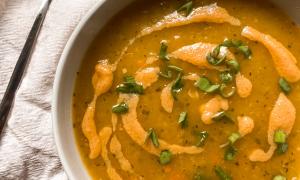 Sopa de miso con calabaza, zanahoria y cúrcuma en bowl blanco sobre tabla de madera