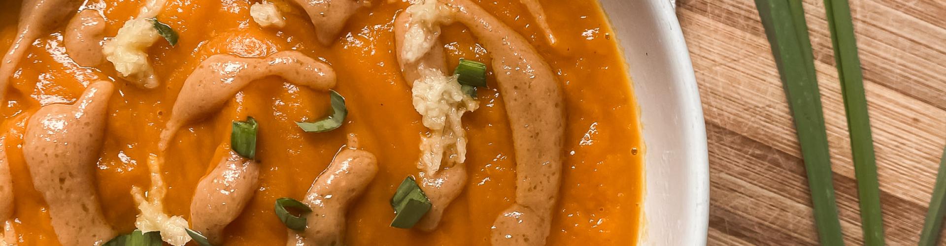Sopa de miso con calabaza, zanahoria y cúrcuma en bowl blanco sobre tabla de madera